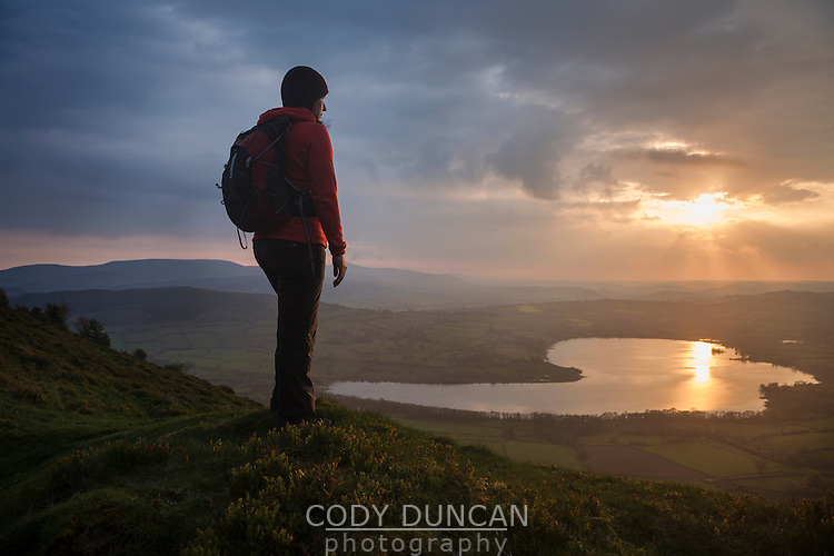 Female hiker takes in view of Llangorse lake from Mynydd Llangorse, Brecon Beacons national park, Wales