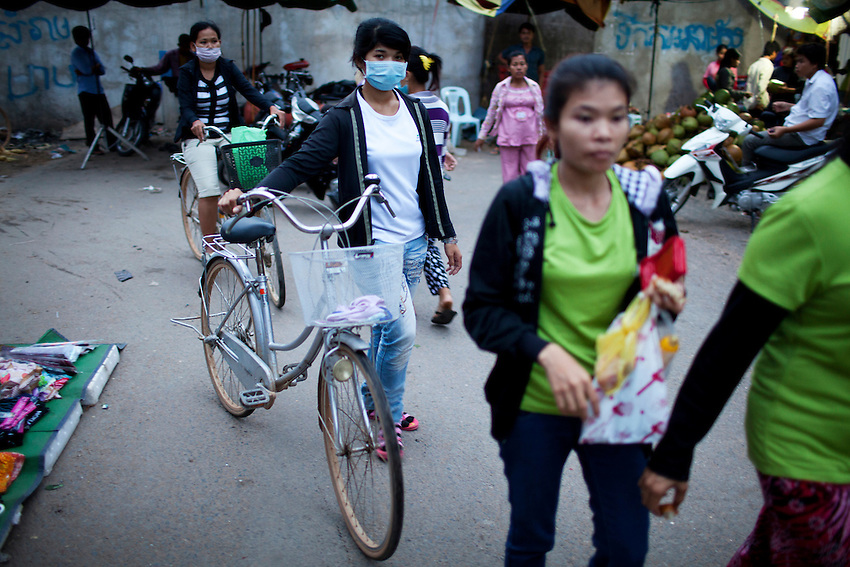 Workers from the Shen Zhou garment factory walk through a small open-air market just after 6 p.m., following the overtime shift, in Phnom Penh, Sept 8, 2011. Standard hours at the factory are 7 a.m. to 4 p.m., with a 1-hour lunch break. Workers receive time and a half for the 2-hour overtime shift, which ends at 6 p.m.