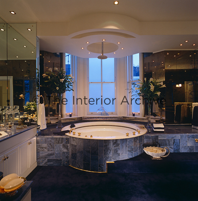 A Hollywood-style bathroom complete with circular Jacuzzi clad in dark blue tiles and a dark blue deep pile carpet