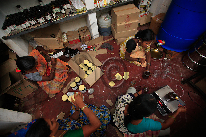 Irula women are fulling honey jars the Hasanur resource center. Last year, Keystone foundation marketed 16 tons of honey. Keystone established resource centers near tribal villages to promote non-timber forest products. Here in Hasanur, seven Irula women from Thaladasalatti are preparing jam, honey, nuts and millet.