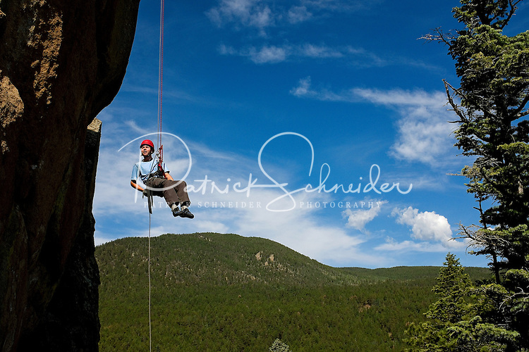 Photo story of Philmont Scout Ranch in Cimarron, New Mexico, taken during a Boy Scout Troop backpack trip in the summer of 2013. Photo is part of a comprehensive picture package which shows in-depth photography of a BSA Ventures crew on a trek. In this photo, a BSA Venture Crew member rappels off of the front face of a natural rock, 60- feet off of the ground. The climbing was taking place at the Cimarroncito Camp in the backcountry at Philmont Scout Ranch. <br />
<br />
The Photo by travel photograph: PatrickschneiderPhoto.com