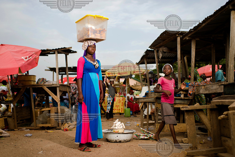 Mariam, approximately 16, in the market in Wa in the Upper West region of Ghana on 28 May 2014. Having completed Grade 5 at school, she says her mother withdrew her about a year ago because she was unhappy with her performance: "My mother said I don't know anything." (Children in Ghana frequently start school late.) Mariam now sells ëchim chimí, a confectionery made from flour, sugar, salt and palm oil. She says she grosses GHS 20.00 - 30.00 (£3.95 - 5.93) per day, selling each item for GHS 0.10 (£0.02), and gives the money she earns to her mother.