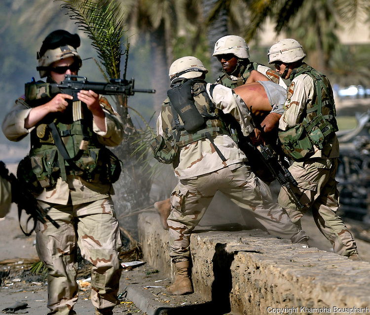 1st Cavalry Divison soldiers arrest an Iraqi while another soldier try to keep a hostile crowd back during a riot in central Baghdad on June 14, 2004. (photo by Khampha Bouaphanh)