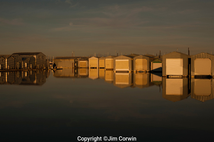 Boathouse reflections in rows along the waterfront at Everett Marina with moon setting