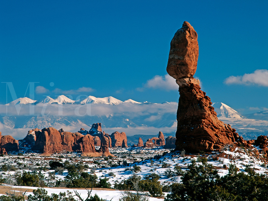 Balanced Rock rises over the Windows Section of Arches National Park in this winter time photograph with the snow capped La Sal Mountains in the background.<br />