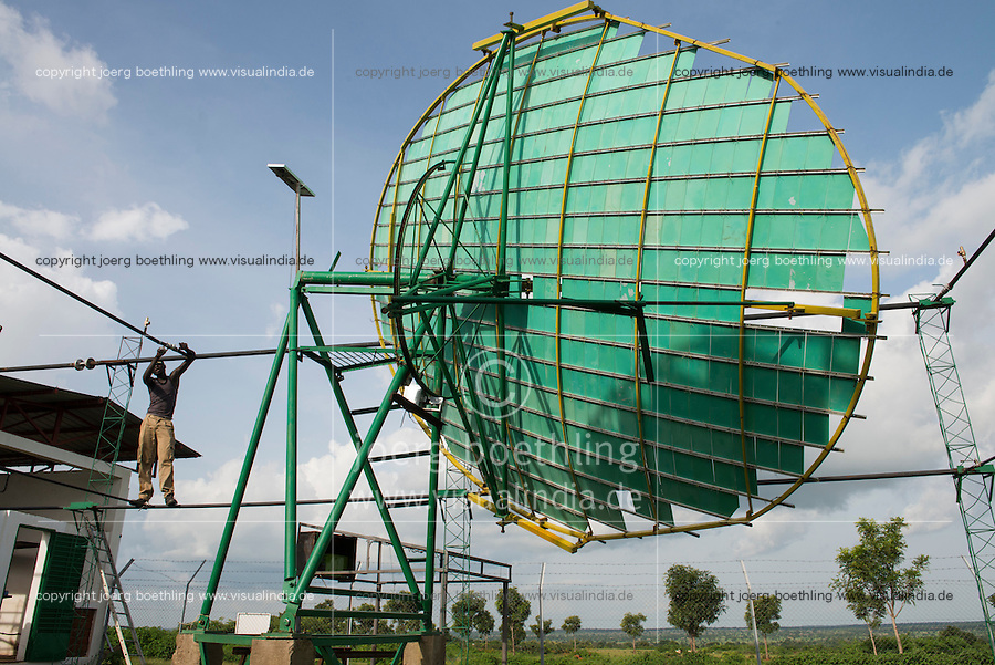 BURKINA FASO, Dano, foundation Dreyer, rice mill with solar cooker, steam is produced by parabolic mirror to process paddy, skilled worker working at water pipe system / BURKINA FASO, Dano, Stiftung Dreyer, Reismuehle mit Solaranlage mit Parabolspiegeln zur Dampferzeugung fuer Reisverarbeitung, Facharbeiter bei Arbeiten am Wasserrohrsystem