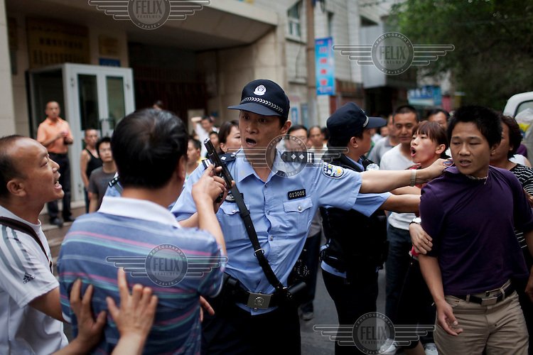 A policeman arrests a Han Chinese man who was part of a mob that chased down a Uighur in Urumqi. They caught up with the Uighur and beat him before the police intervened firing shots in the air and arresting the two Han attackers. The mob then attacked the police to try and stop the arrests. Ethnic violence between the Uighur and Han people had erupted in the city a few days earlier.
