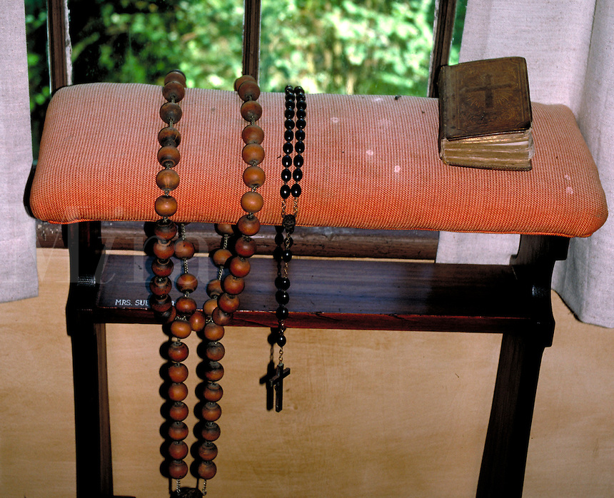 Old, oversized, Catholic Rosary prayer beads are placed on a bench next to a Bible or prayer book. Displayed in the Rural Life Museum of Lafayette, Louisiana. Lafayette Louisiana, Rural Life Museum.