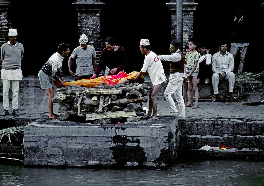 A human body is layed on a CREMATION GHAT at the Hindu Temple complex of PASHUPATINATH where the ashes will be swept into the BAGMATI RIVER - KATHAMANDU, NEPAL