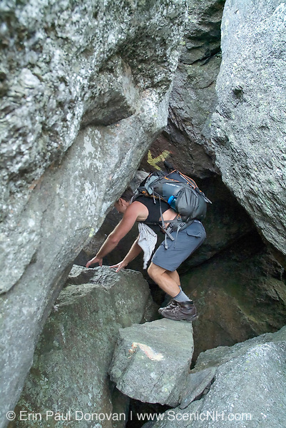 Hiker on the Subway Trail in the White Mountains, New Hampshire USA. The Subway Trail is a side trail off the King Ravine Trail, which travels through a large boulder field in King Ravine. The subway reconnects with the King Ravine Trail. Snow can be found in the ice caves of this ravine during the summer months.