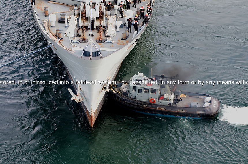 Navy ship being pushed by a tug boat