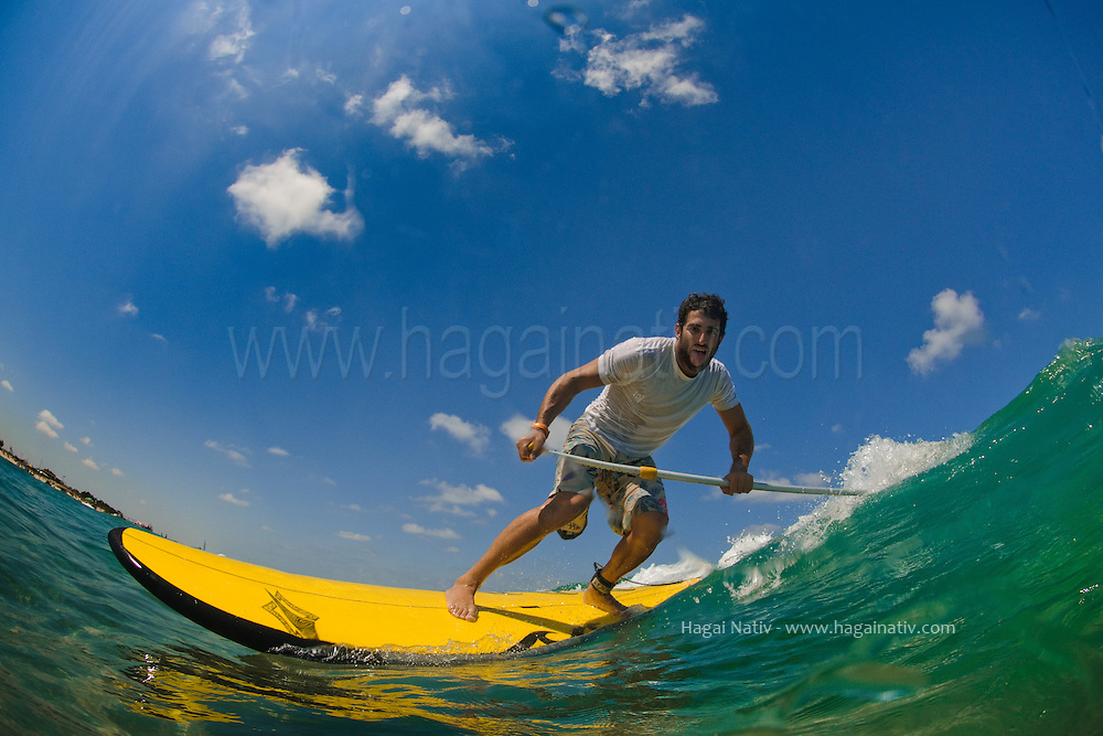 SUP (Stand Up Paddle-board) surfer, Stav Cnaani, enjoys the hot meditarrenean water of June at the beach of Israel