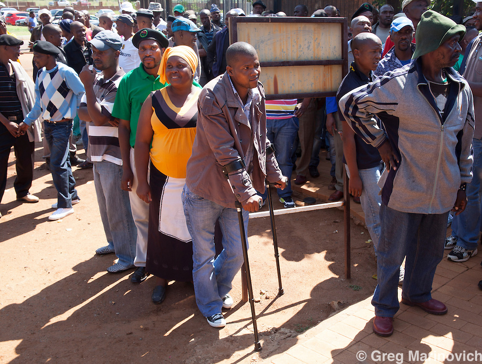 Wonderkop, Marikana, North West South Africa Feb 12, 2013. Mzoxolo Magidiwana, on crutches, claims the police shot him while he lay wounded at Marikana on Aug 16th. The 276 miners who were arrested following the Marikana massacre of August 16 1012 and their supporters travel to Garankuwa magistrates court on charges of public violence. Their court date was postponed to October. Photo Greg Marinovich