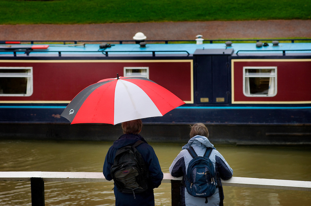 Visitors watch the boats in wet weather at Foxton Locks on the Grand Union Canal, Leicestershire, England, Europe, UK.