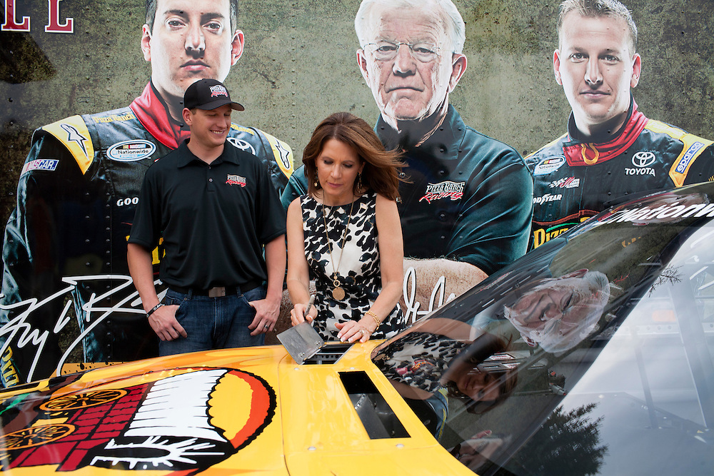 Republican presidential hopeful Michele Bachmann, right, looks at the racecar belonging to driver Michael McDowell of Joe Gibbs Racing, left, after a campaign stop on Friday, August 5, 2011 in Newton, IA.