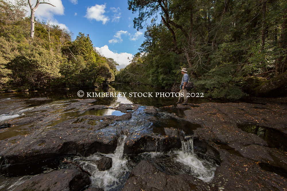 A bushwalker rests beside a river on the Lees Paddock Track, near Mersey Forest, on the edge of the Cradle Mountain Lake St Clair National Park in Tasmania.