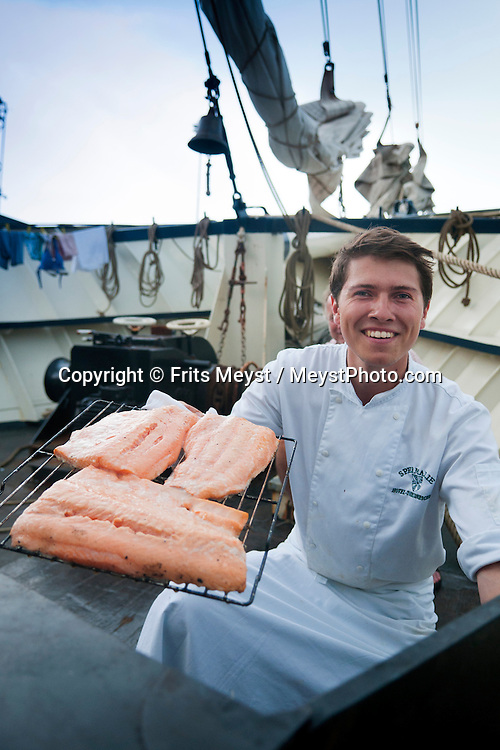 Ireland, July 2013. Chef Jelle Dam smoked his own Salmon on board. It is the first time that Tallship Thalassa, a barquentine sailing vessel with 3 masts, sails from Belfast to Galway along the Irish coastline. While a full-rigged ship is square-rigged on all three masts, and the barque is square-rigged on the foremast and main, the barquentine extends the principle by making only the foremast square-rigged. The advantages of a smaller crew, good performance before the wind and the ability to sail relatively close to the wind while carrying plenty of cargo made it a popular rig at the end of the 19th century. Photo by Frits Meyst/Adventure4ver.com