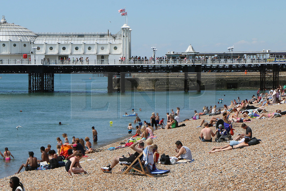 © Licensed to London News Pictures. 29/07/2014. Brighton, UK. people relaxing and sunbathing on Brighton beach. The weather has returned to sunny and hot after yesterday morning’s torrential rains with temperatures expected to reach around the 23C in Brighton and the South Coast. Photo credit : Hugo Michiels/LNP