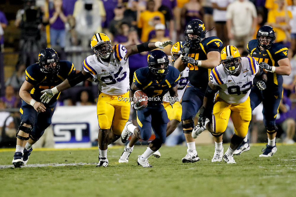 Sep 25, 2010; Baton Rouge, LA, USA; West Virginia Mountaineers running back Noel Devine (7) runs away from LSU Tigers defensive tackle Drake Nevis (92) and defensive tackle Lazarius Levingston (95) during the second half at Tiger Stadium. LSU defeated West Virginia 20-14. Mandatory Credit: Derick E. Hingle