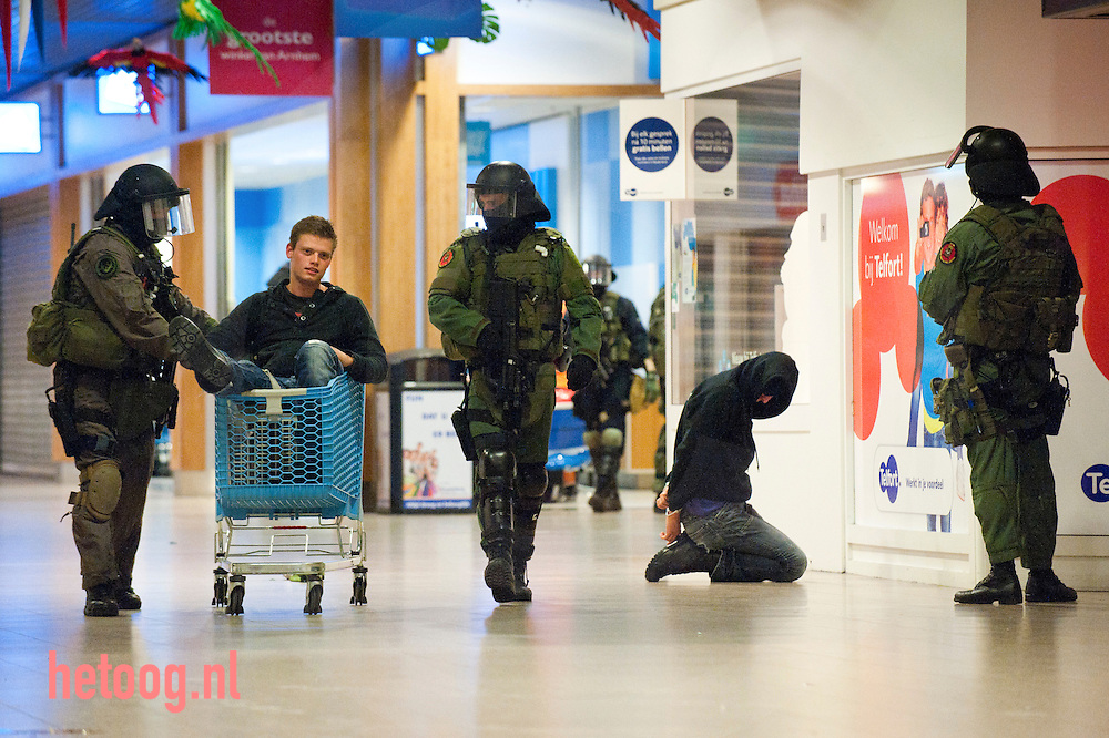 nederland, arnhem 07juni2012 antiterreuroefening pers uitgenodigd door defendie. persbericht van Rijksoverheid:.UIM oefent terreurbestrijding..De Unit Interventie Mariniers, de antiterreureenheid van Defensie, traint donderdagavond in Winkelcentrum Kronenburg, Arnhem diverse procedures om een terroristische aanslag te beëindigen. ..De Unit Interventie Mariniers (UIM) is de specialistische eenheid van het Korps Mariniers voor inzet bij grootschalige en complexe terreurbestrijding in Nederland. Voor deze nationale veiligheidstaak staat de UIM continu gereed voor inzet. Om de gehele keten van alarmering, inzetbaarheid, planning van een actie en uitvoering te doorlopen, vinden regelmatig oefeningen plaats. ..Tot het werkterrein van de eenheid behoren vliegtuigen, schepen, boorplatformen, treinen en complexe gebouwen, zoals voetbalstadions, theaters of winkelcentra. Naast specialist in het zware interventie werk, heeft elk team binnen de UIM een eigen specialisme. Zo zijn er klimteams voor urban climbing, duikteams en zogenoemde breach teams voor het forceren van toegang. De UIM, voorheen de Bijzondere Bijstandseenheid (BBE), werd in 1973 opgericht na het gijzelingsdrama tijdens de Olympische Spelen in München. ..Juist gisteren hebben voormalige BBE-leden door Minister van Defensie Hans Hillen toegezegd gekregen dat ze alsnog een onderscheiding krijgen voor hun inzet tijdens de ontzetting van treinkaping ?de Punt? en de gijzeling van leerkrachten van een school in Bovensmilde in juni 1977.