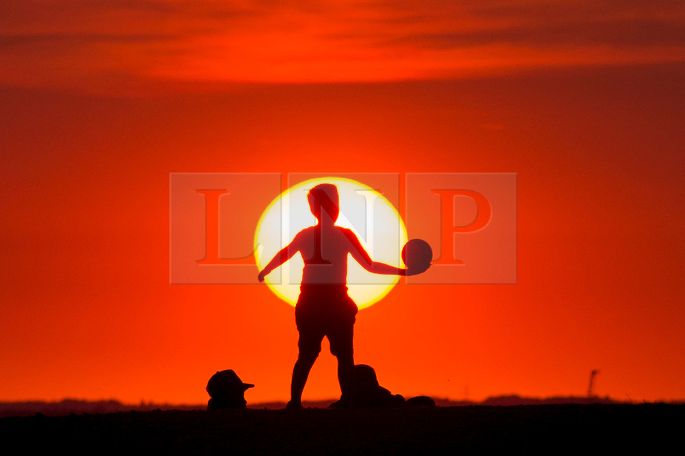 © Licensed to London News Pictures. 25/07/2018. LONDON, UK. People watch the sunset at Northala Fields in Northolt, West London, after another day when temperatures reached 30C. The forecast is for temperatures to increase further to 35C by the end of the week. Photo credit: Stephen Chung/LNP