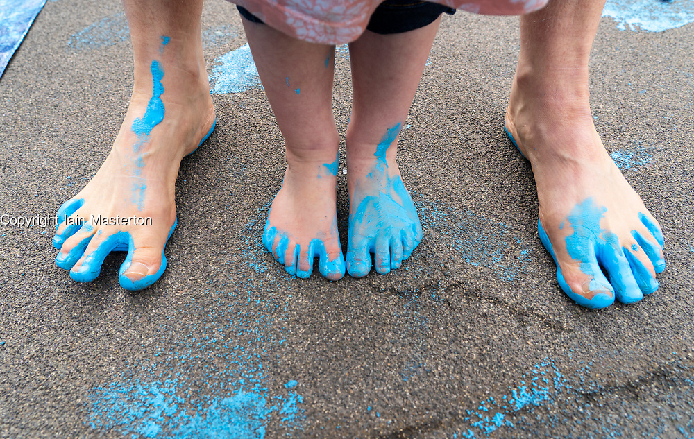 Glasgow, Scotland, UK. 21 March, 2019. A 'Blue Wave' demonstration by the Extinction Rebellion climate change protest group saw protesters make blue footprints, made from water-soluble paint, across George Square to the City Chambers. The peaceful protest briefly held up traffic. The Group aims to highlight threat of rising water levels in the River Clyde and of global climate change. Pic; Mother and daughter with blue paint on feet during protest.