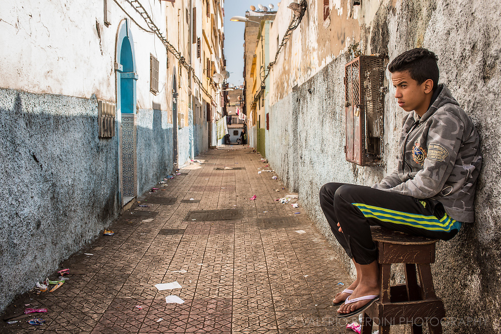 A boy sits at the entrance of a narrow street in the old medina of Casablanca