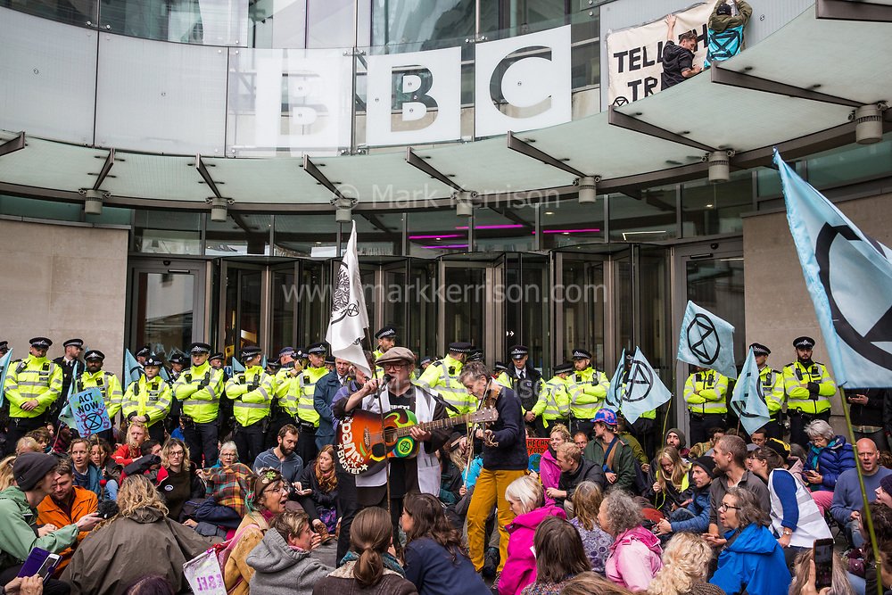 London, UK. 11 October, 2019. Climate activists from Extinction Rebellion, including two standing on the glass parapet, block the main entrance to the BBC’s New Broadcasting House on the fifth day of International Rebellion protests. They were demanding that the broadcaster ‘tell the truth’ regarding the climate emergency.