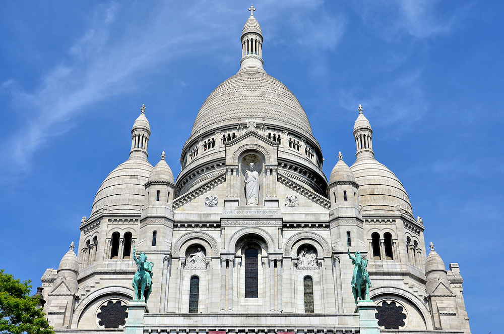 Basilique du Sacré-Cœur in Paris, France<br />
On the highest hill in Paris, butte Montmartre, stands the majestic Roman Catholic church called Sacré-Cœur or the Basilica of the Sacred Heart of Paris. Its bright white stone, 272 foot dome and equestrian statues of Joan of Arc and King Saint Louis IX are spectacular to view at ground level and it becomes more impressive during the exhausting 234 steps to the top. Or you can ride the funicular to see this beautiful, Romanesque-Byzantine church that was completed in 1914. The summit also provides a wonderful view of the city.