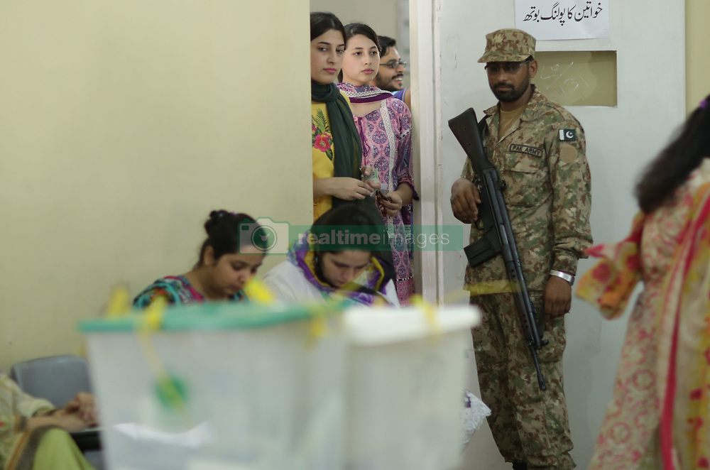 July 25, 2018 - Lahore, Punjab, Pakistan - Voters casts their vote while Military officials and polling staff watch at a polling station during Pakistan's general election in Lahore on July 25, 2018. Pakistanis are voting today in a closely fought election that will determine the course of the nuclear-armed nation central to U.S. anti-terrorism efforts and Chinas global infrastructure ambitions. Pakistanis voted July 25 in elections that could propel former World Cup cricketer Imran Khan to power, as security fears intensified with a voting-day blast that killed at least 28 after a campaign marred by claims of military interference. Polling began at 8AM and will conclude, without any break, at 6PM across the country's 85,307 polling stations, of which 17,007 have been declared highly sensitive. (Credit Image: © Rana Sajid Hussain/Pacific Press via ZUMA Wire)