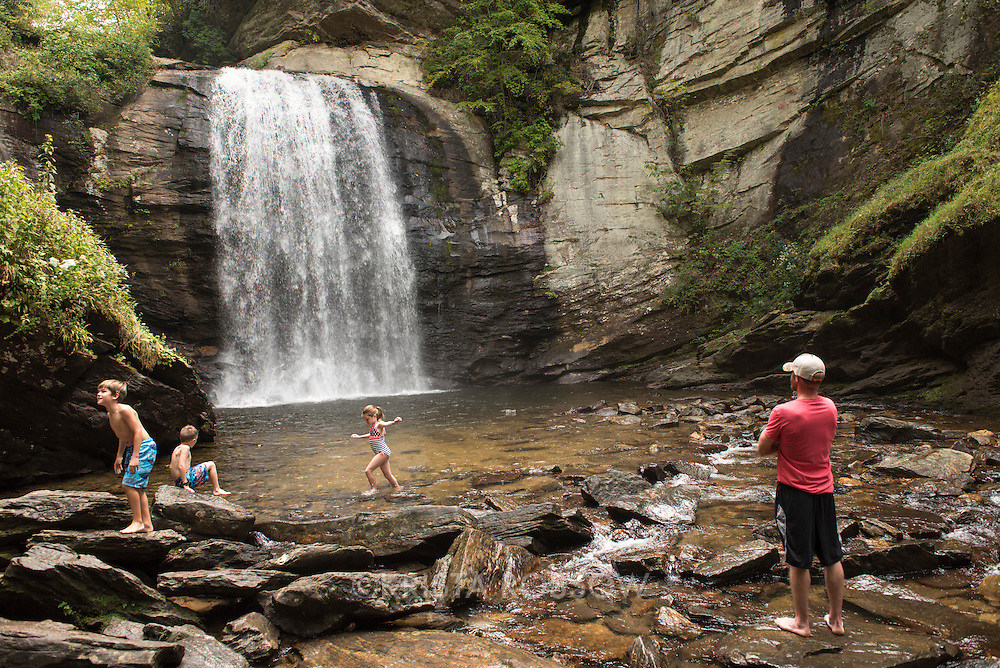 A family plays in the water at Looking Glass Falls , a popular waterfall and swimming hole in the Pisgah National Forest located near Brevard, North Carolina, southwest of Asheville and about 10 miles off of the Blue Ridge Parkway.